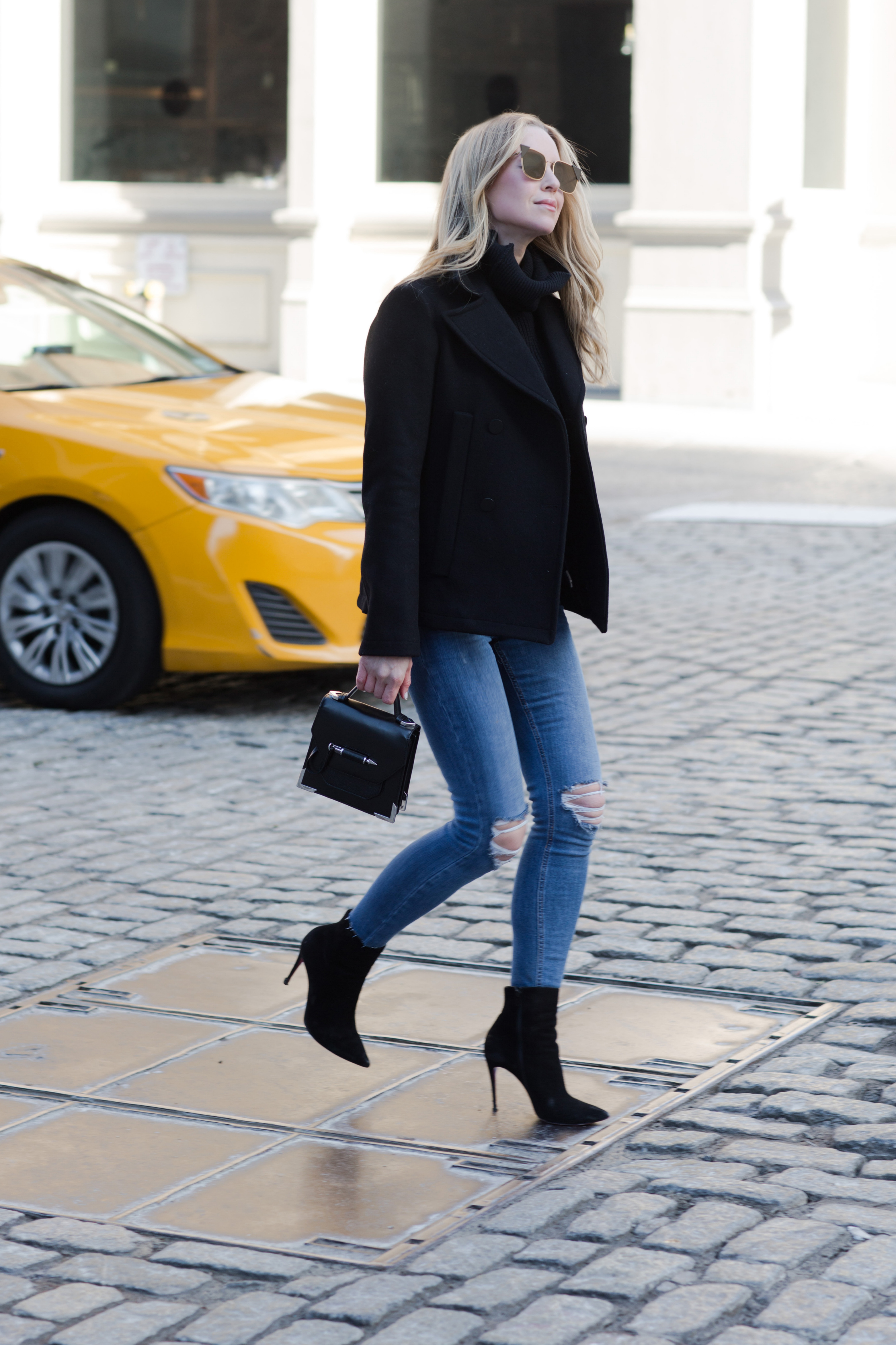 winter work day outfits inspiration - Helena Glazer of Brooklyn Blonde wearing Slate & Stone black Peacoat with black turtleneck sweater, distressed denim, Louboutin boots, Fendi Sunglasses, and Mackage handbag