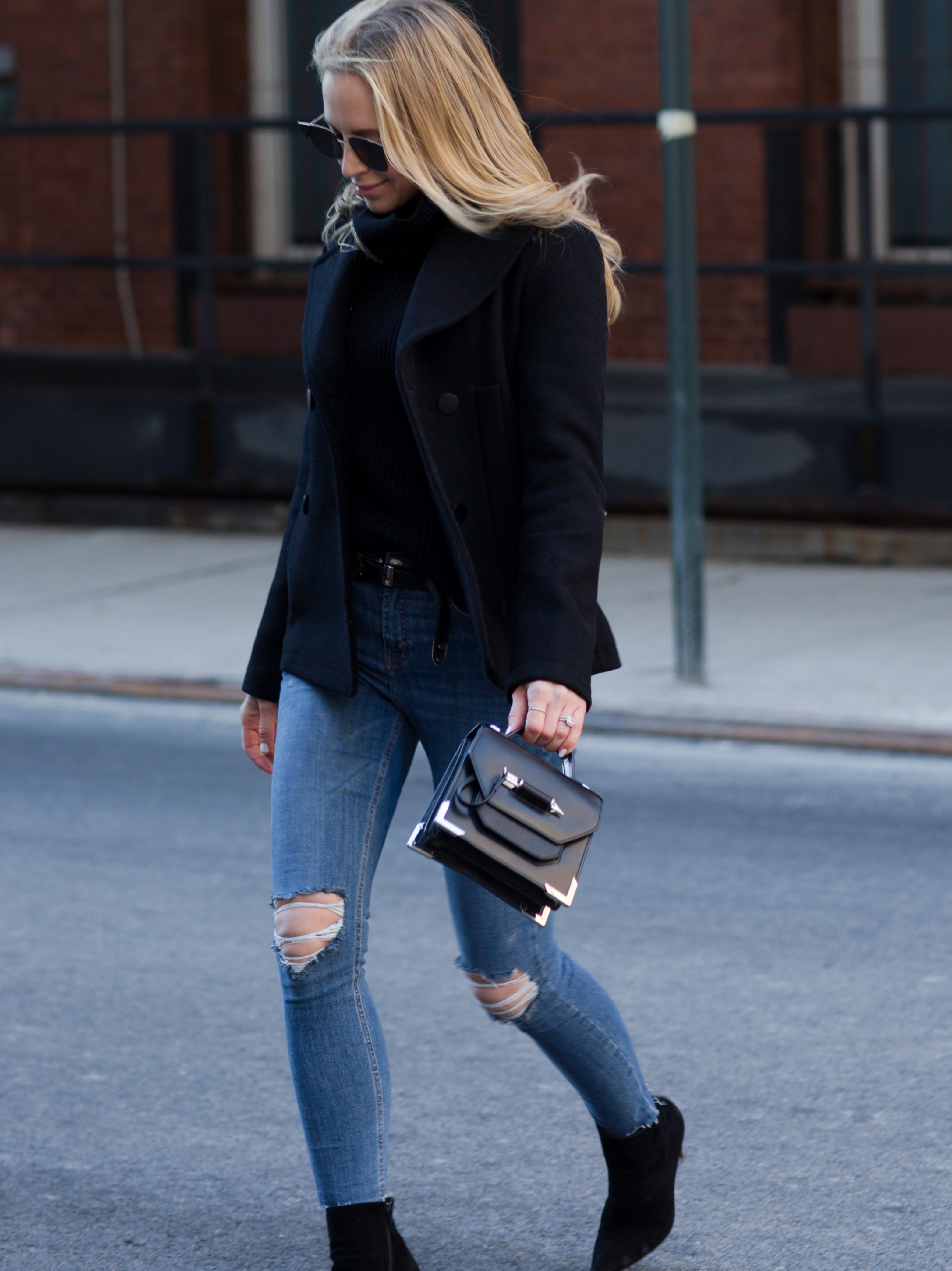 winter work day outfits inspiration - Helena Glazer of Brooklyn Blonde wearing Slate & Stone black Peacoat with black turtleneck sweater, distressed denim, Louboutin boots, Fendi Sunglasses, and Mackage handbag