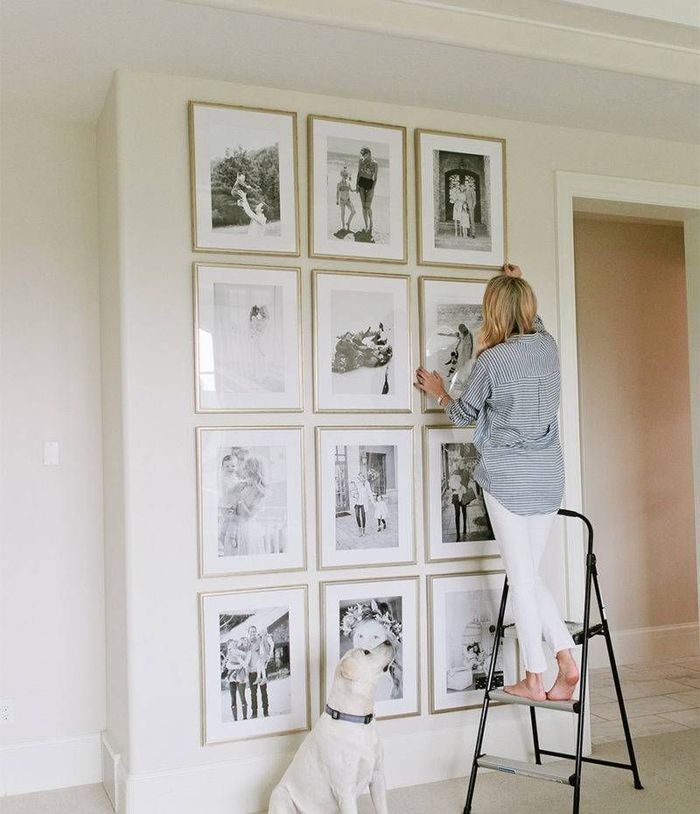 woman hanging framed photos 