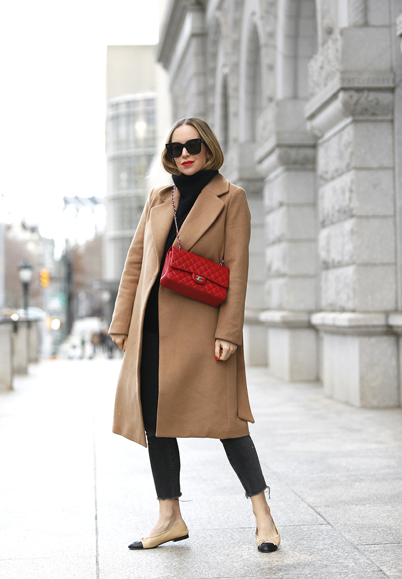 woman wearing trench coat, red sling bag, and black outfit