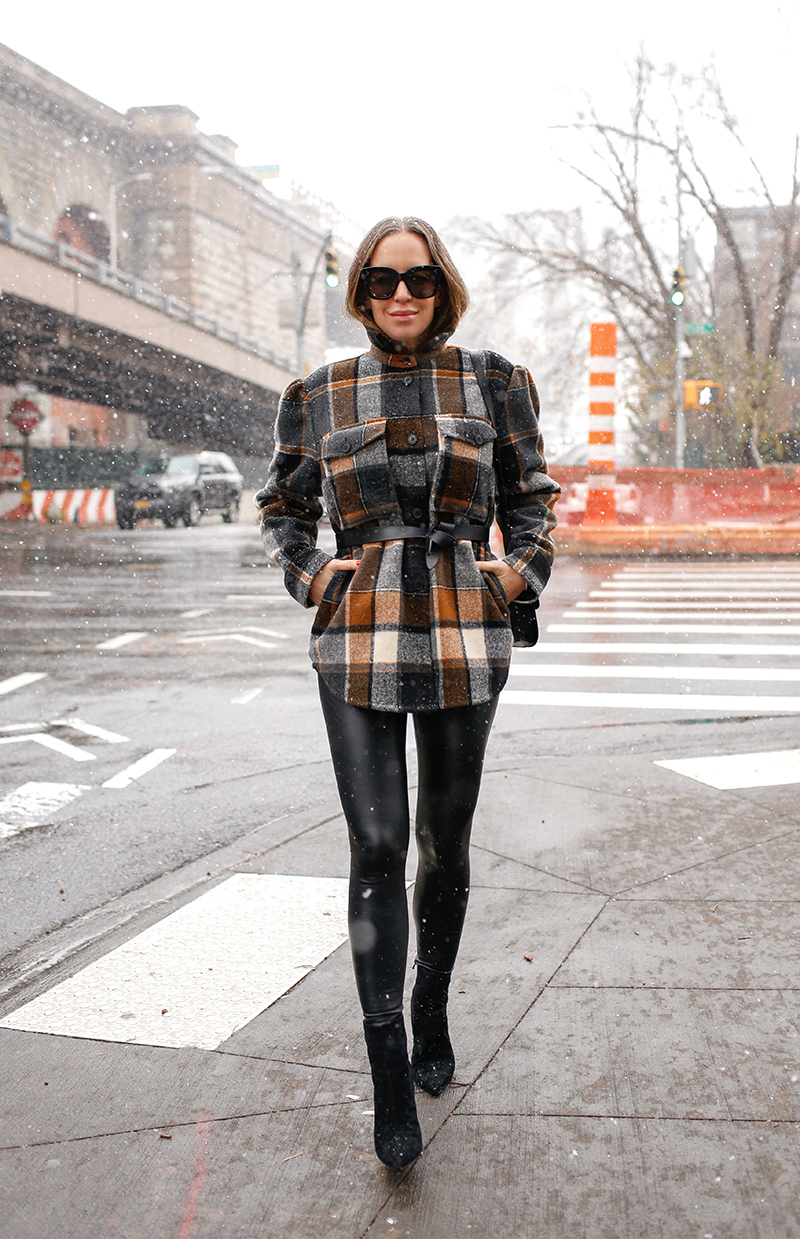 woman in the snow wearing leather tights, sweater, and sunglasses