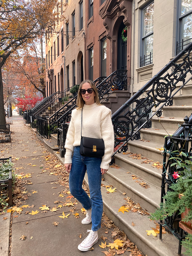 woman wearing sweater, jeans, white sneakers and her favorite pair of sunglasses