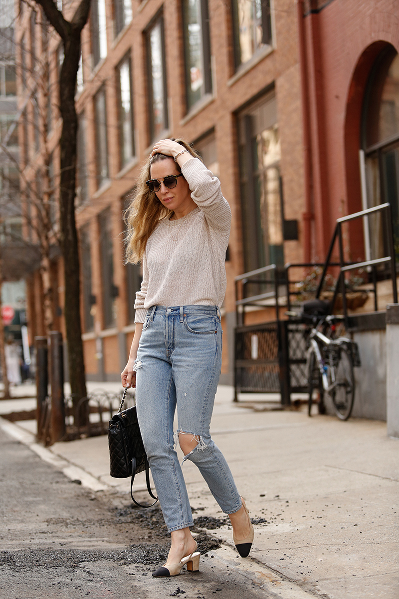 woman wearing her favorite Pairs of Denim, a sweater, and touching her hair