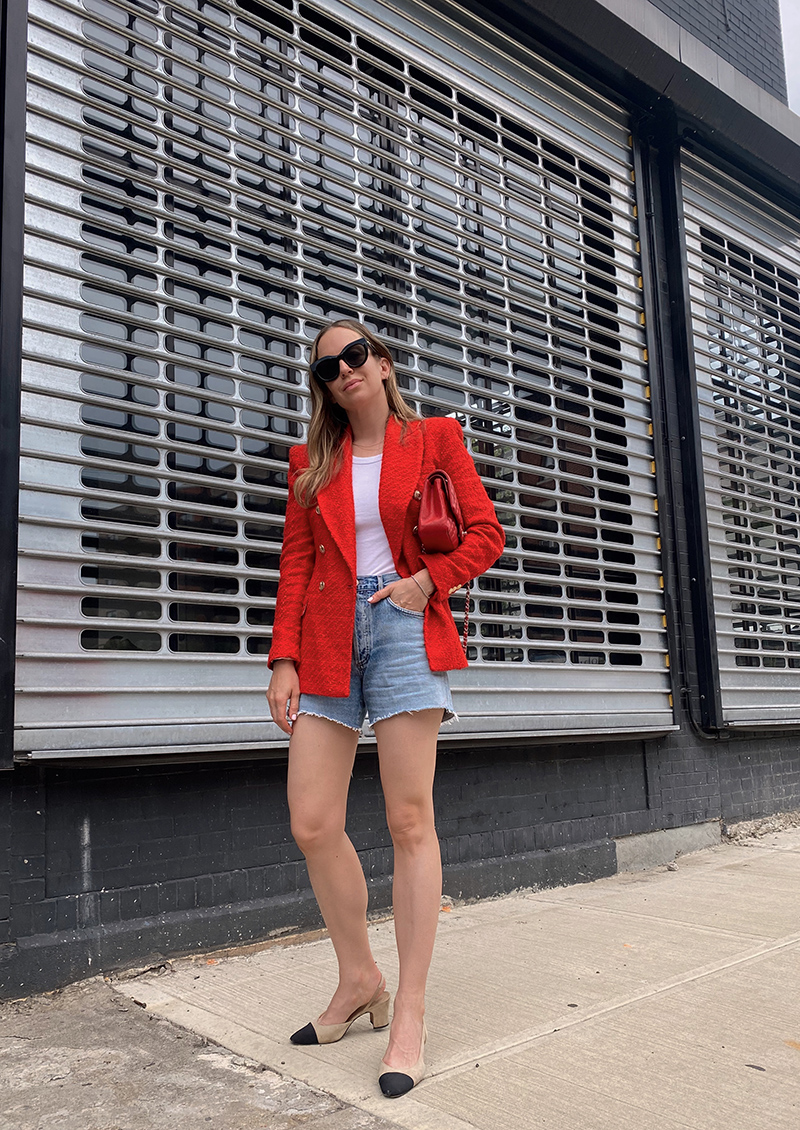 woman wearing white top, denim shorts, and red blazer