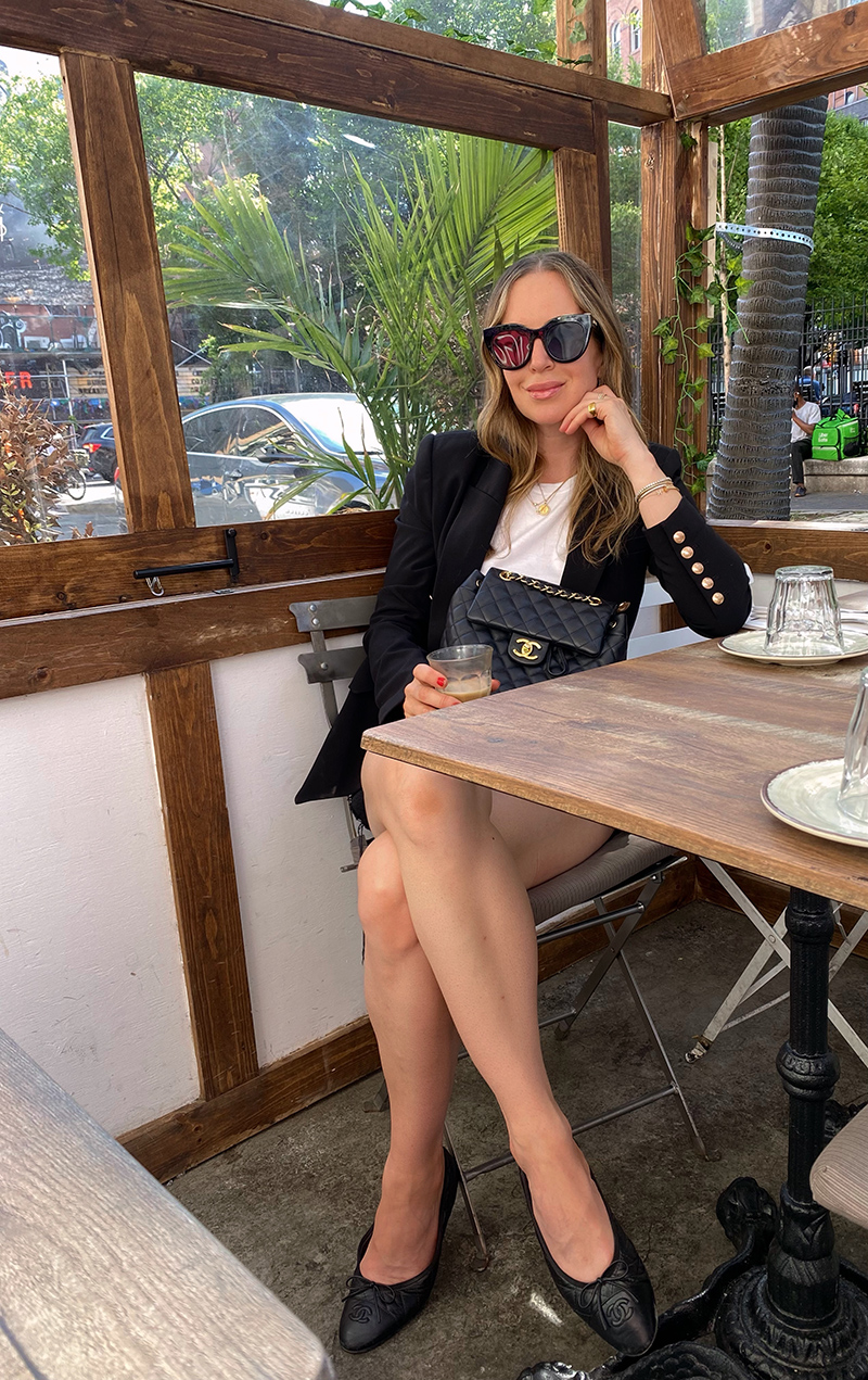 woman wearing black blazer and white shirt and leaning on a table sharing pieces I've been wearing