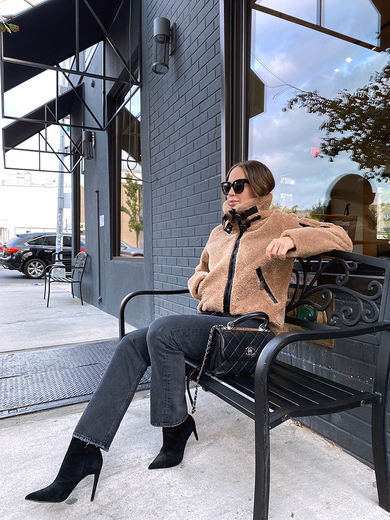 woman sitting outside a store and wearing 90s jeans and jacket from Shopbop Sale