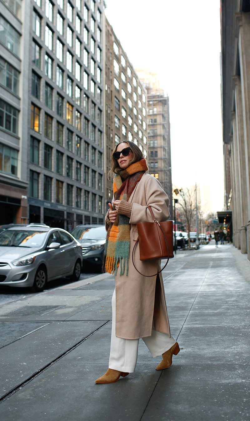 woman sharing Winter Wear with plaid scarf and white pants and bucket bag