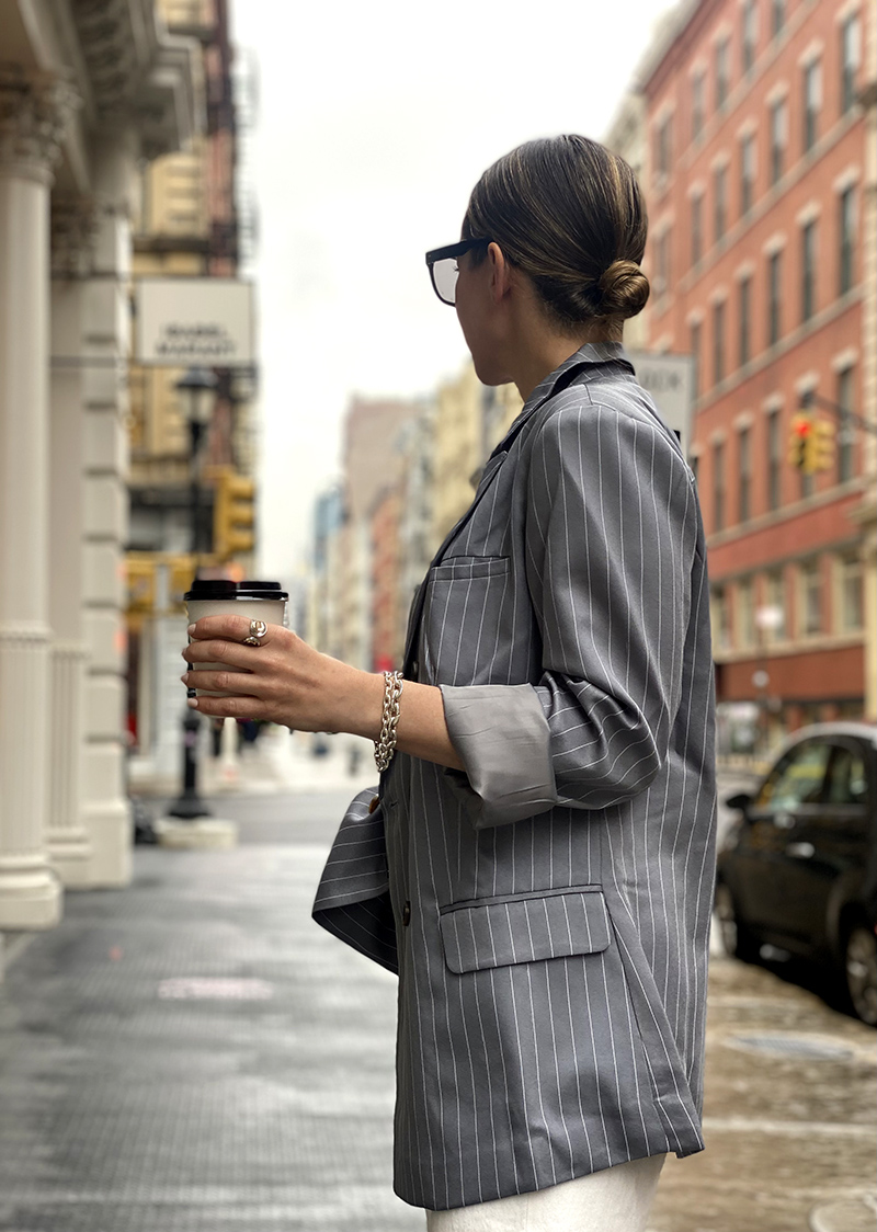 woman in Pinstripes and Denim Trousers and holding coffee cup