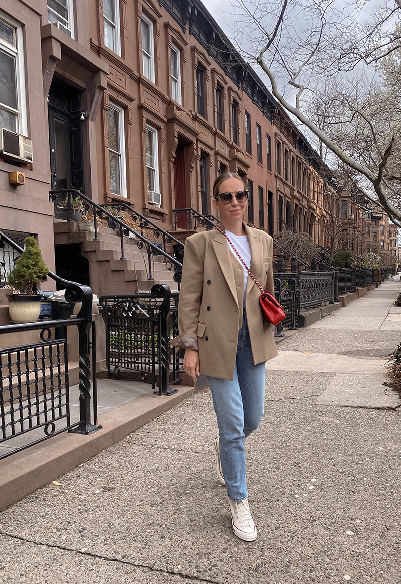 woman in white shirt, denim pants, and brown jacket as one of her Mom-Friendly Outfits