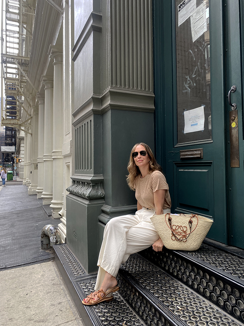 woman sitting on stairs and wearing shirt, wide legged pants and sarah flint sandals 