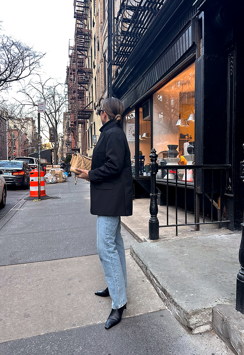 woman with ponytail hair wearing oversized blazer, turtle neck, jeans, and boots